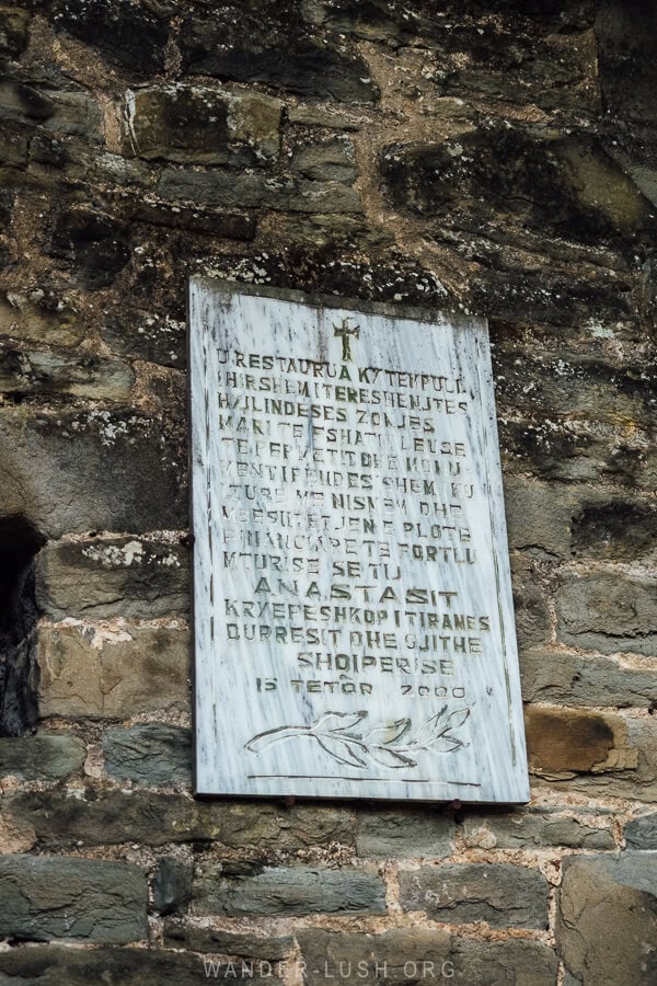 A sign on a stone wall outside the Church of Leus.