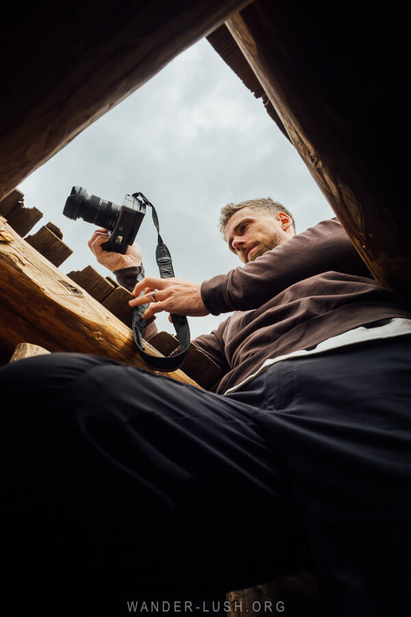 A man pokes his head out the top of a Svan tower to photograph the view.