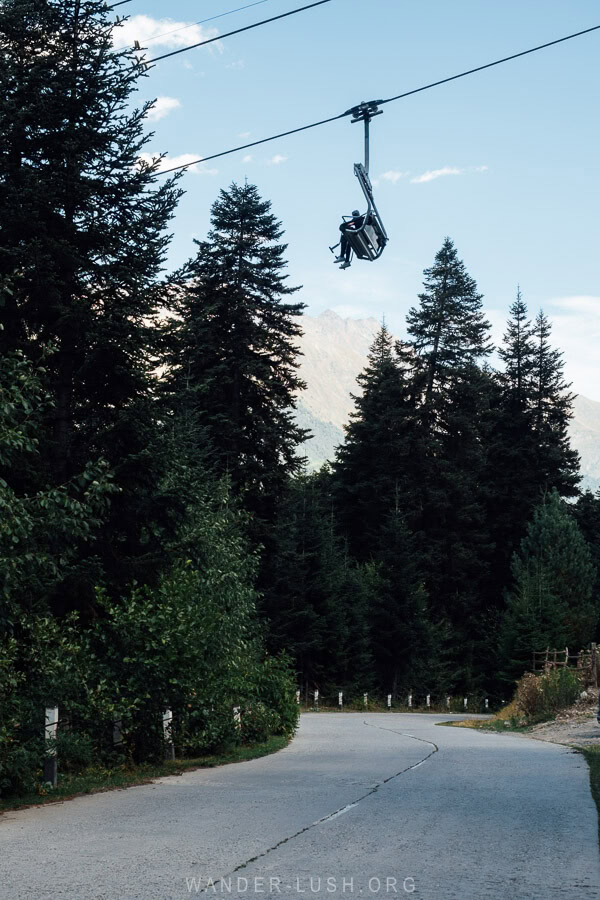 A ski lift passes over a road between the trees in Mestia.