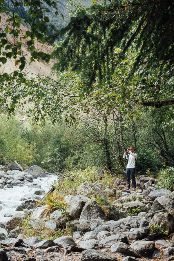 A man points a camera on the trail on the Mestia Chalaadi Glacier hike.