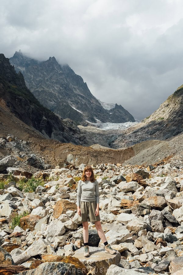 A woman standing on rocks in front of Chalaadi Glacier.