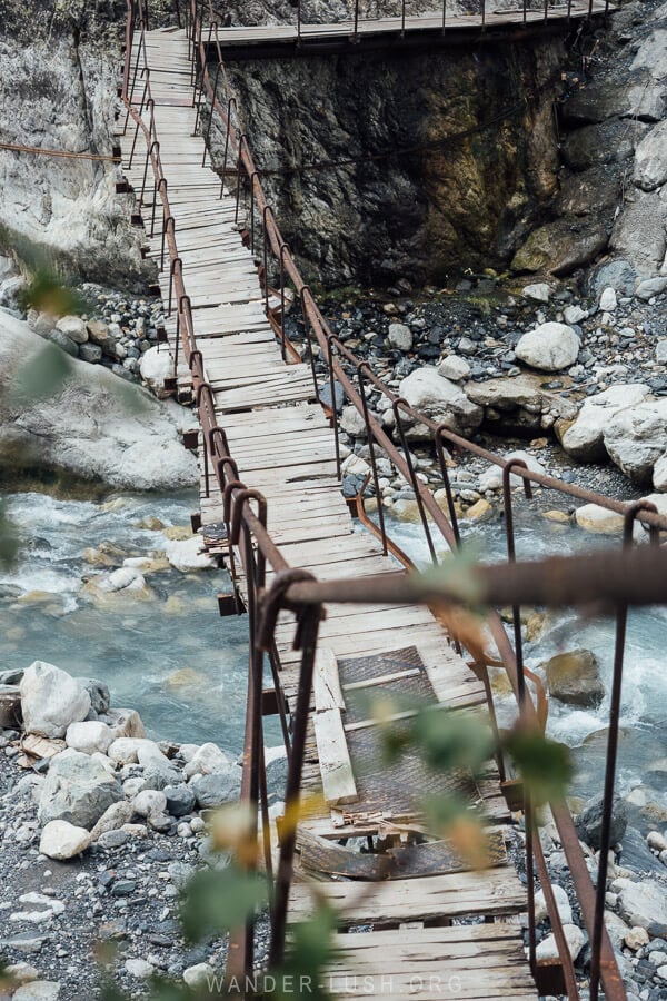 An old wooden bridge spans the river on the way to the Chalaadi Glacier.