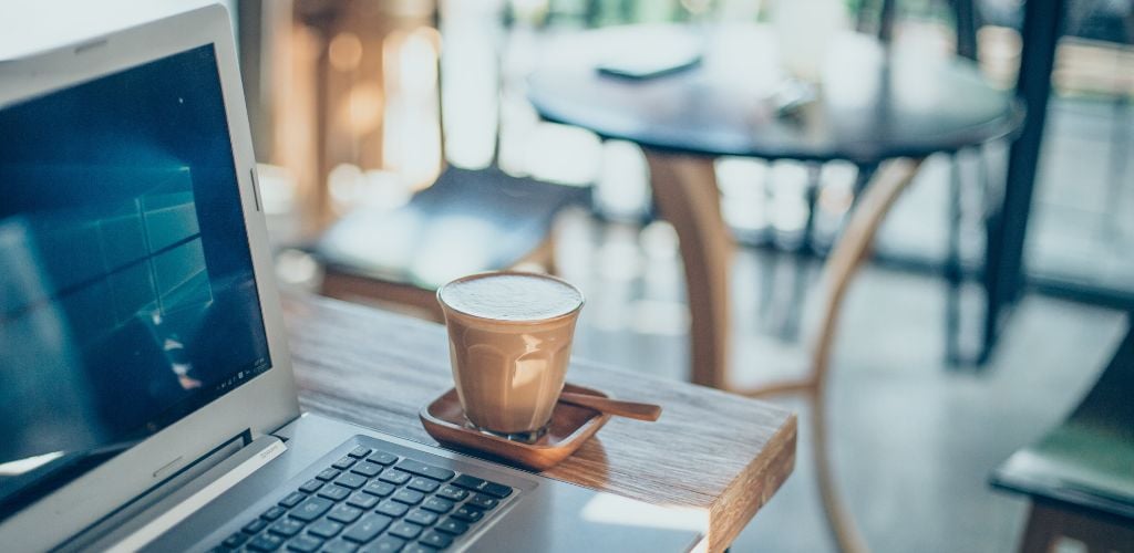 cafe laptop on small table with coffee on side