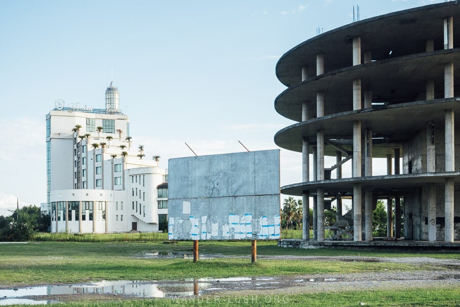 A blank billboard stands in front of an abandoned resort and a half-finished concrete building in Anaklia, Georgia.