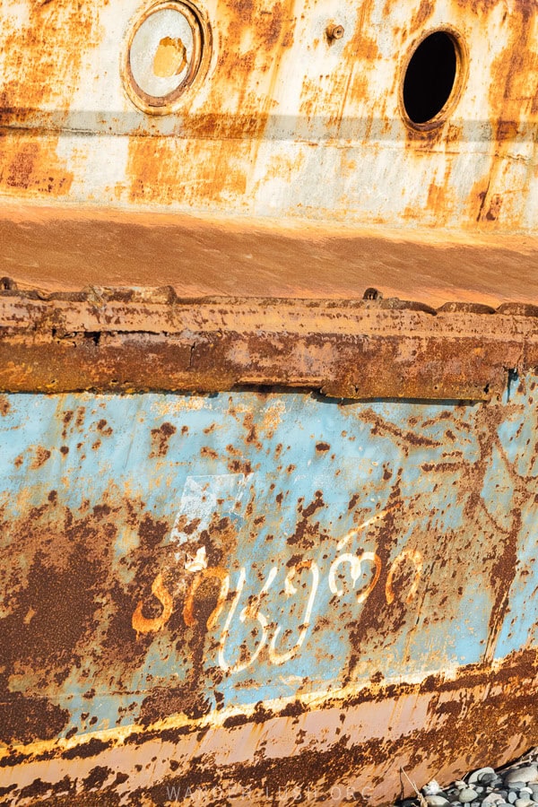 Details of the Morskoy Konik shipwreck in Anaklia, with Georgian script painted on one of its rusted sides.