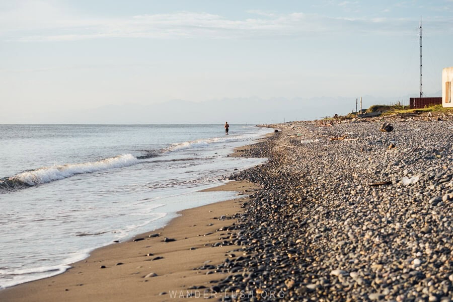 A lone fisherman stands knee-deep in the water on Ganmukhuri Beach near Abkhazia.