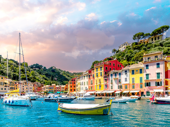 Boats in the water at an Italian port lined with colorful buildings.