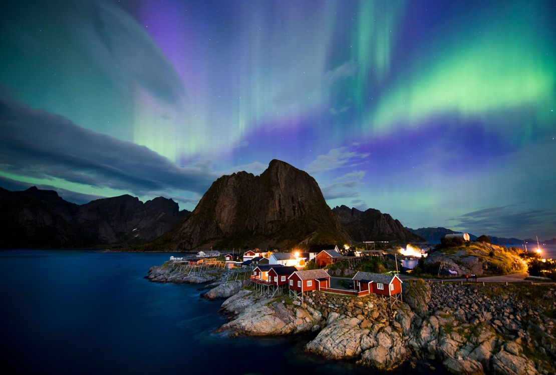 The Northern Lights illuminate the sky over Reinefjorden in Reine in the Lofoten Islands in Norway.