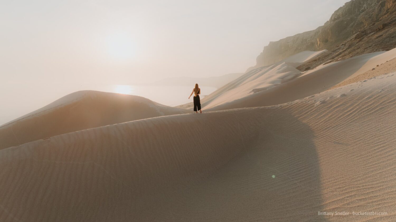 Woman atop dunes for sunrise at Archer Beach Sand Dunes on Socotra Island, Yemen.