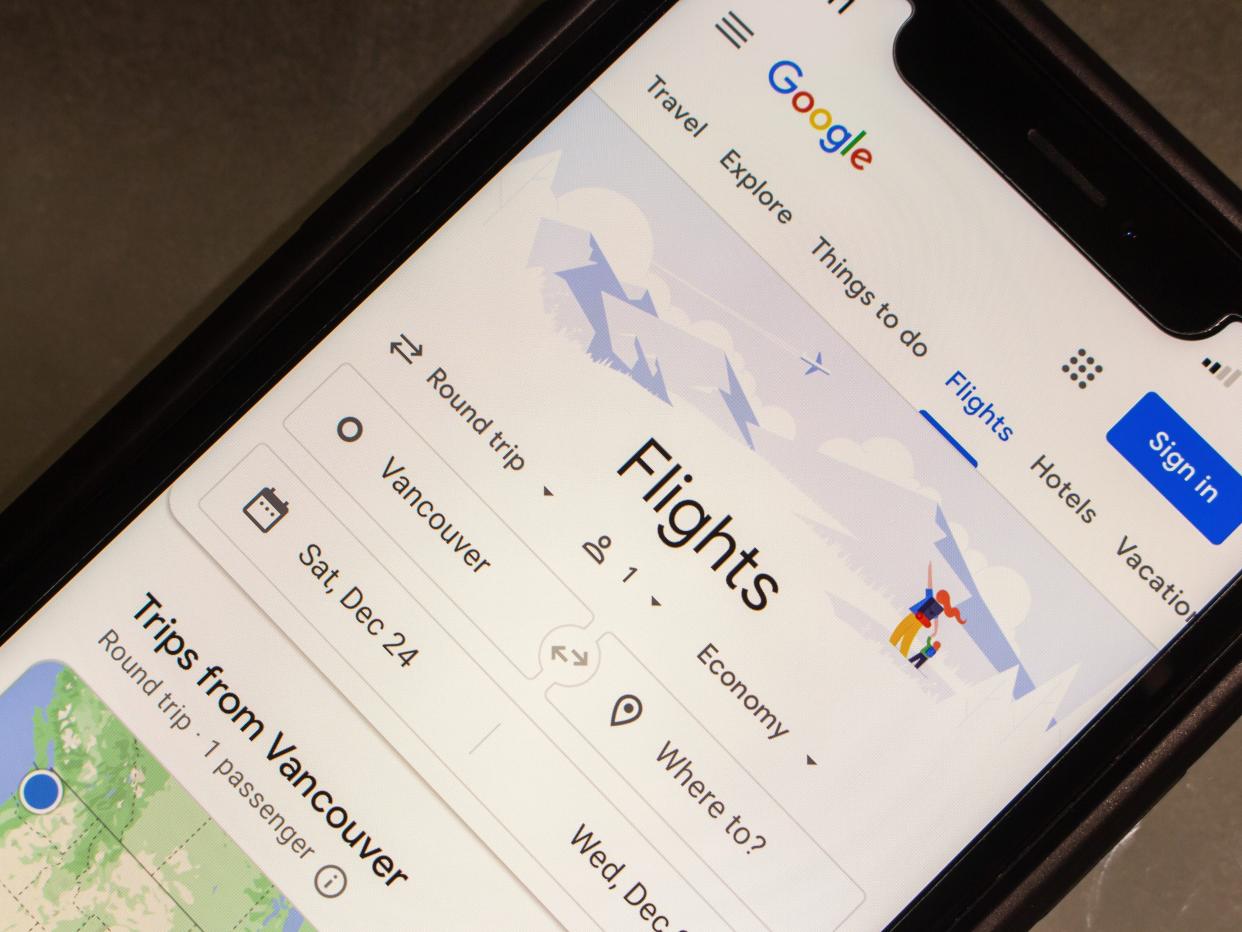 An image of a phone with the Google Flights app open on it.