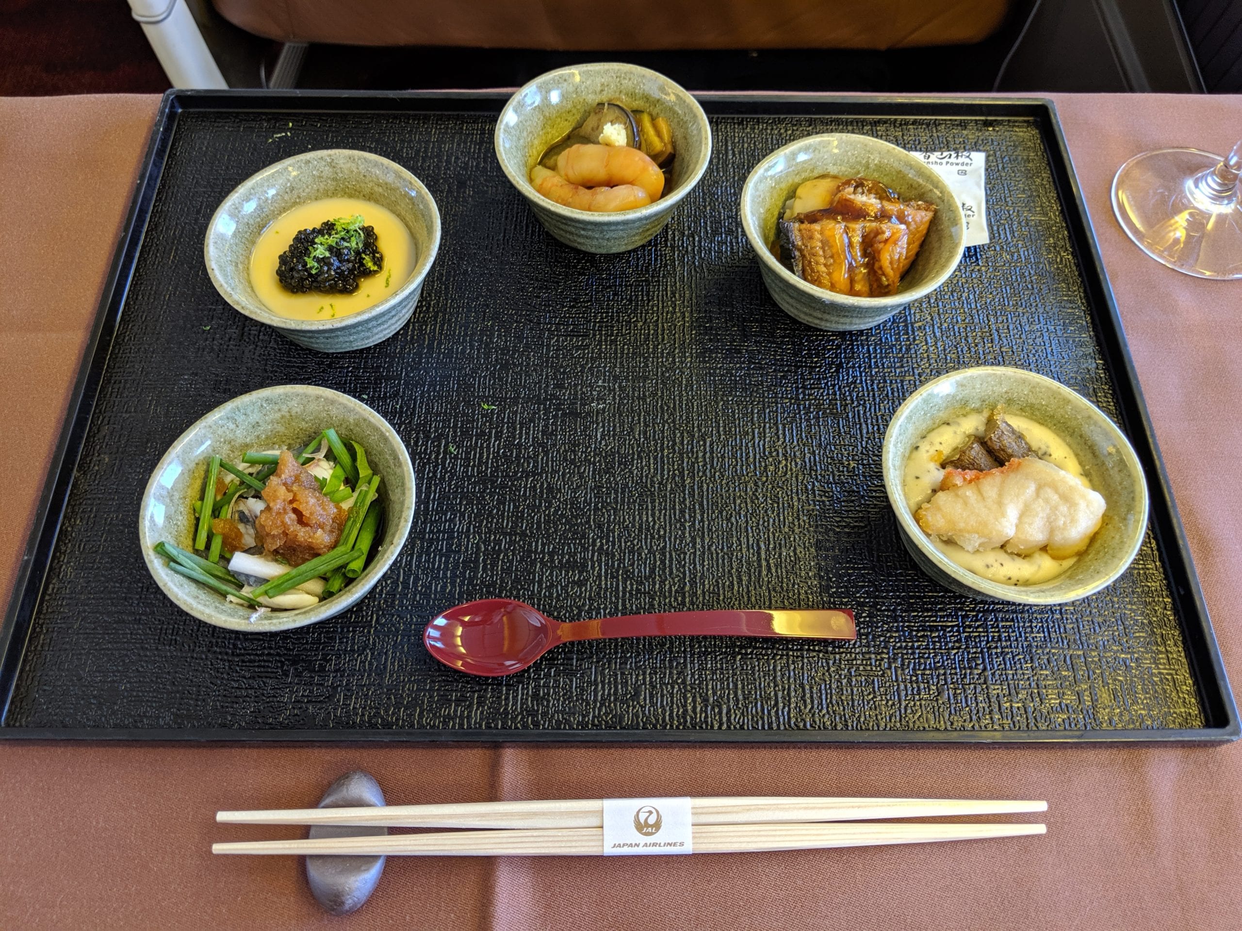 five dishes on a tray table in japan airlines first class 