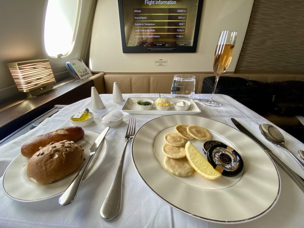 caviar, bread, and a glass of champagne on the tray table in the etihad first class apartment