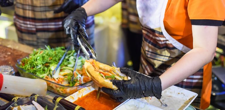 Vietnamese woman serving traditional vietnamese sandwich banh mi street food at night