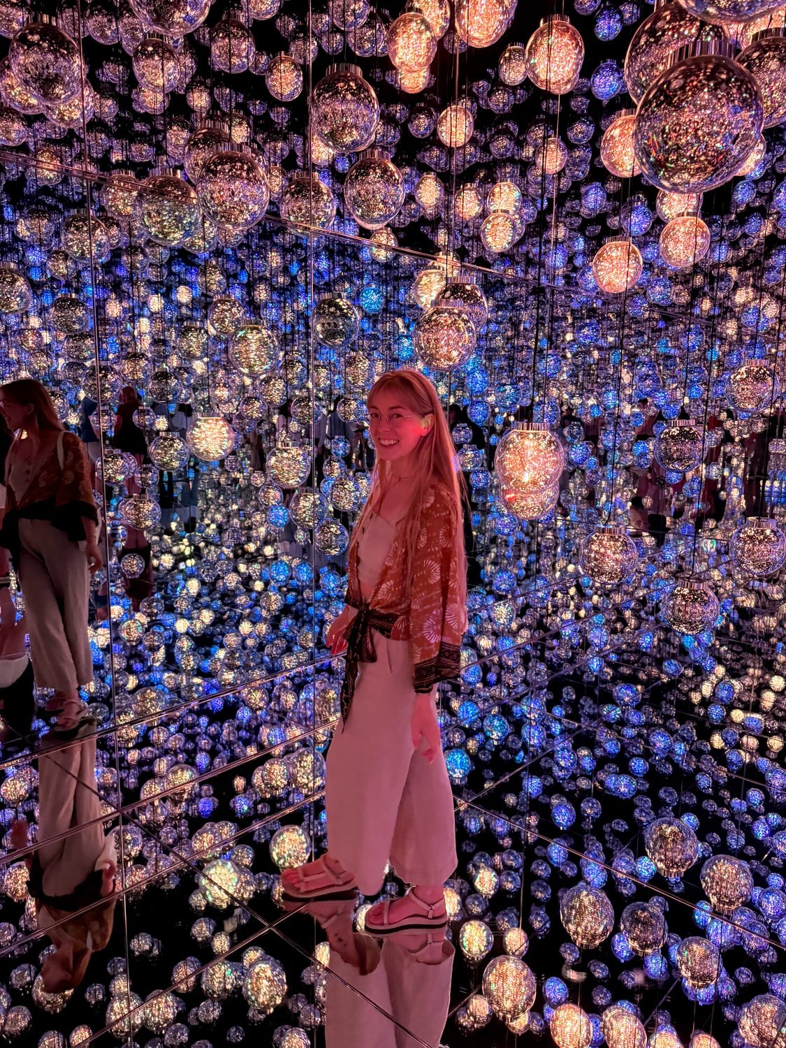 A digital nomad girl poses for a photo inside teamLab Borderless digital art museum in Tokyo, Japan.