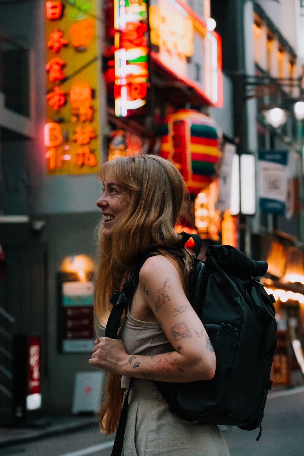 Bucketlist Bri, a digital nomad girl living in Tokyo, Japan on a colorful neon-lit street in Shibuya.