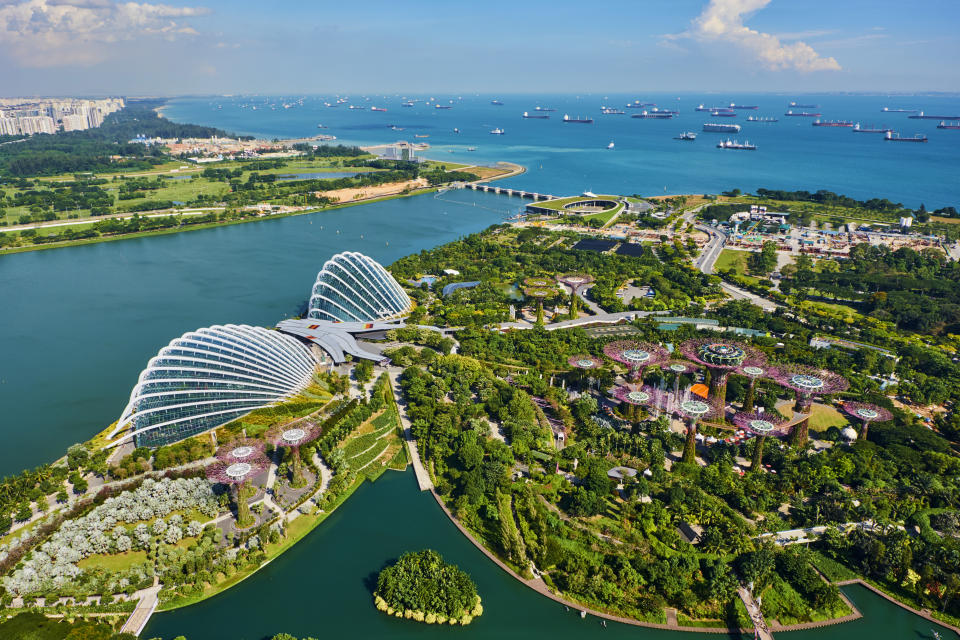 Aerial view of Singapore with various buildings, greenery, and boats.