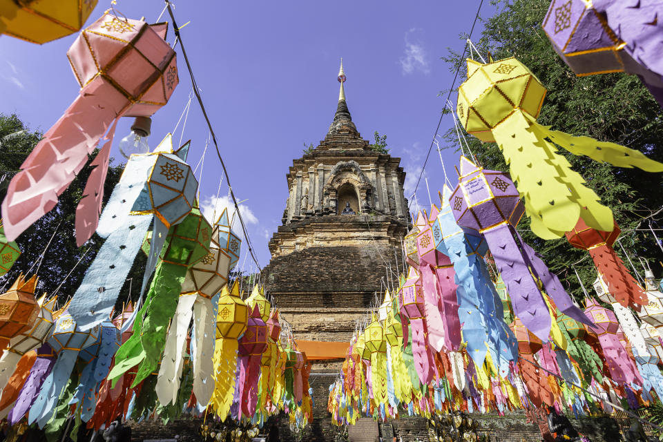 Colorful lanterns hanging in front of a historic pagoda, with a clear sky in the background in&nbsp;Chiang Mai, Thailand.