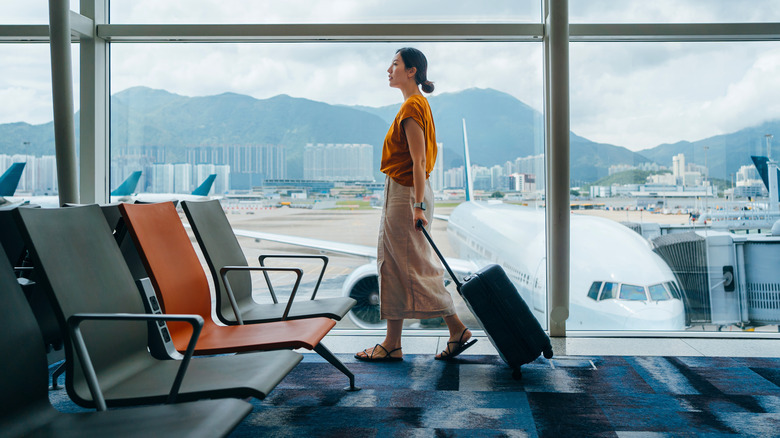 Woman at airport wheeling around luggage.