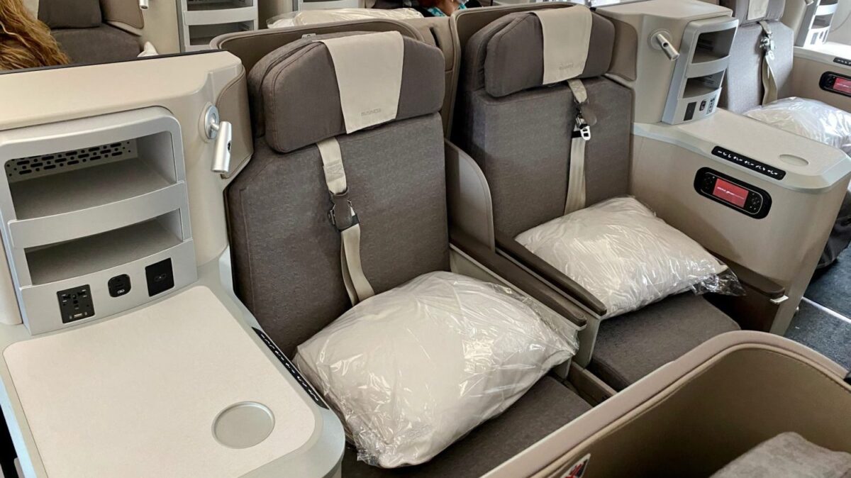 two business class seats with pillows and side tables 