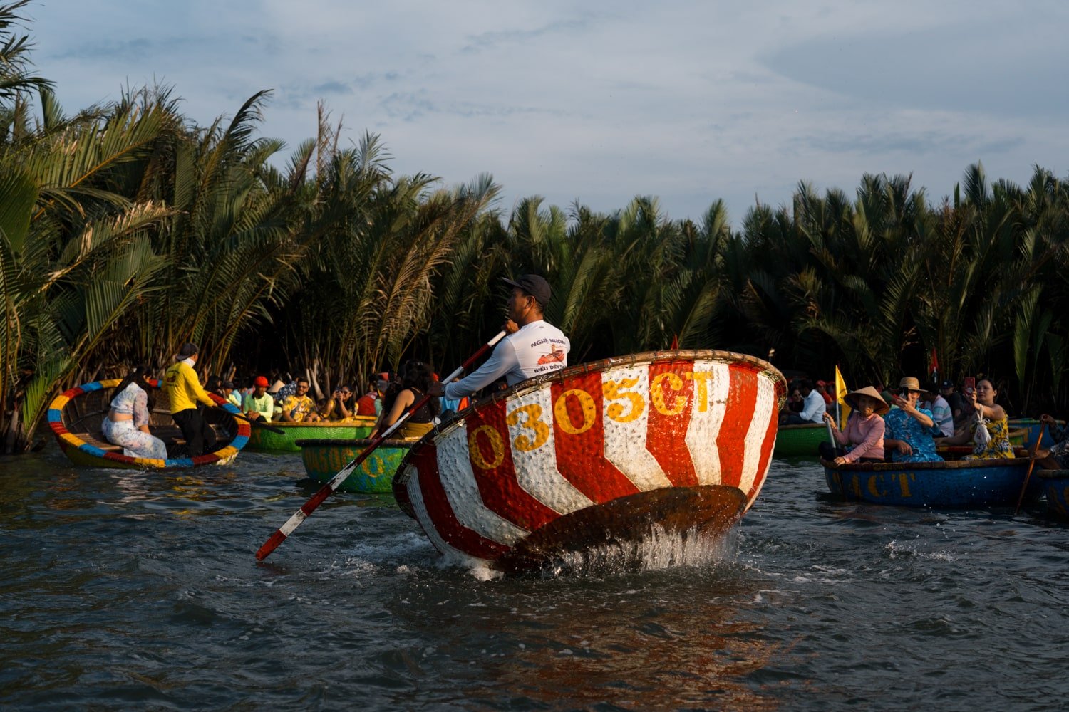 A Vietnamese local man dances and spins a basket boat in the Bay Mau Coconut Forest near Hoi An, Vietnam.