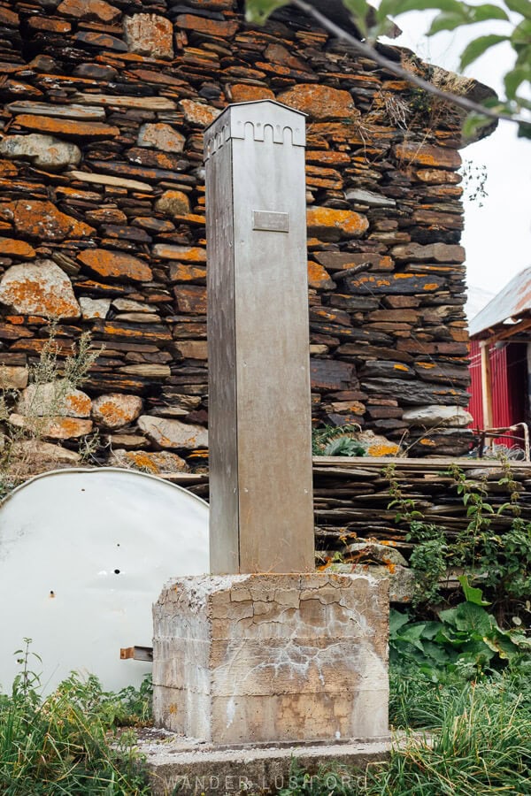 A modern metal monument shaped like a traditional tower in Ushguli.