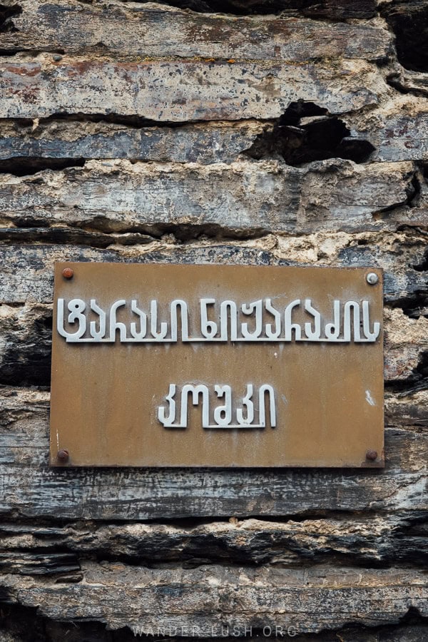 A metal plate mounted to a stone tower in Ushguli with the name of the family tower in Georgian script.