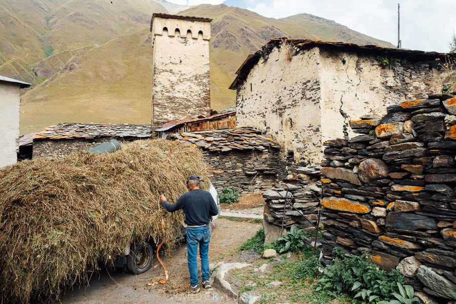 A man ties hay to his truck on the streets of Ushguli in preparation for winter.