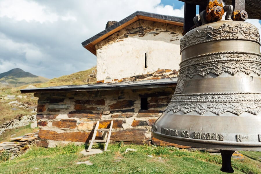 Chazhashi Church, a small stone and mortar church in Ushguli with a bell hanging in the yard.