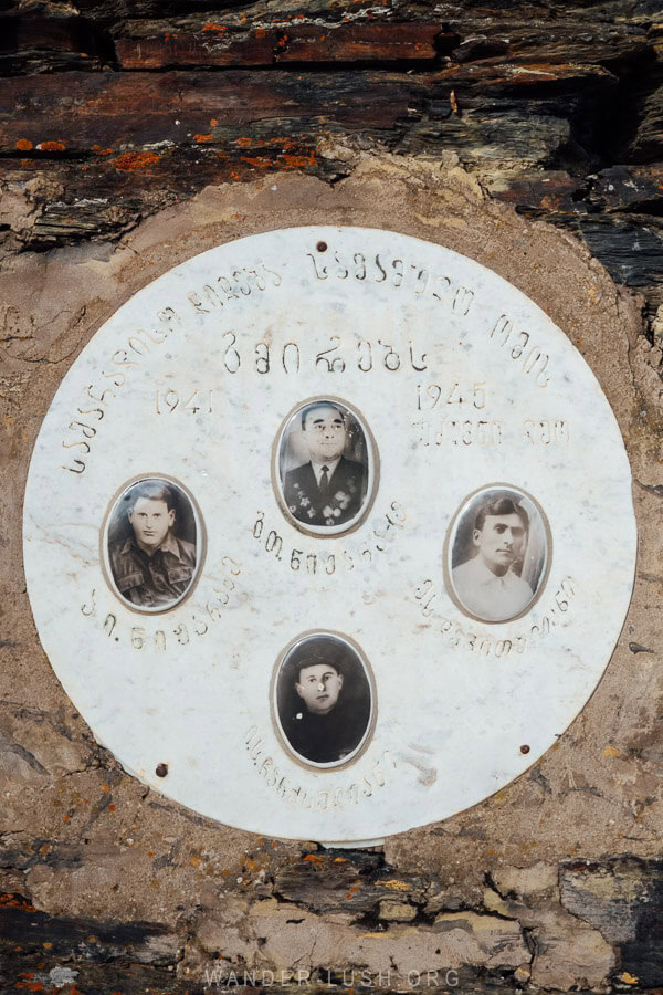 A memorial plaque with the faces of fallen soldiers mounted to a historic tower in Ushguli, Georgia.