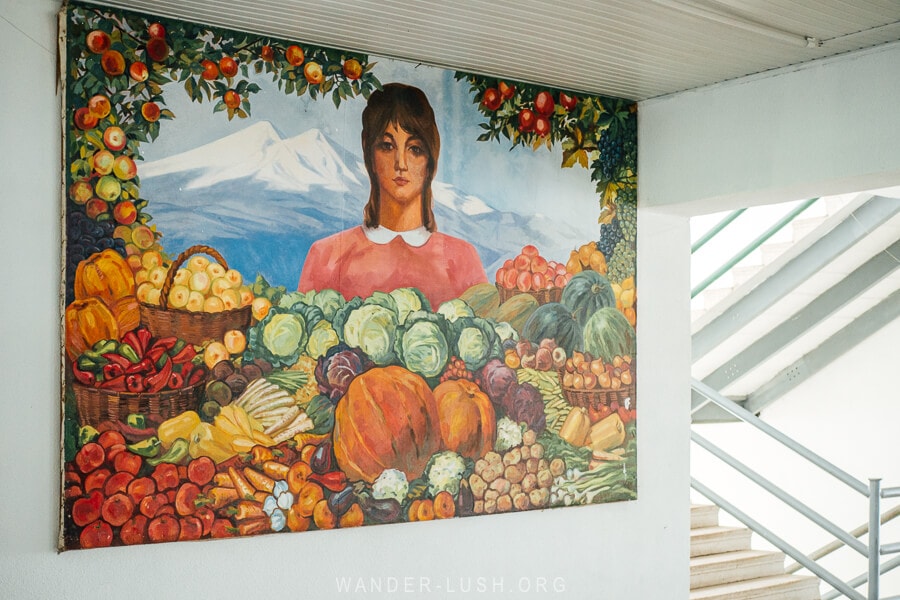 An artwork depicts a woman surrounded by fruit and vegetables inside the agricultural market in Poti.