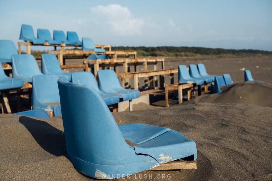 An abandoned grandstand with blue plastic chairs on Poti Beach.