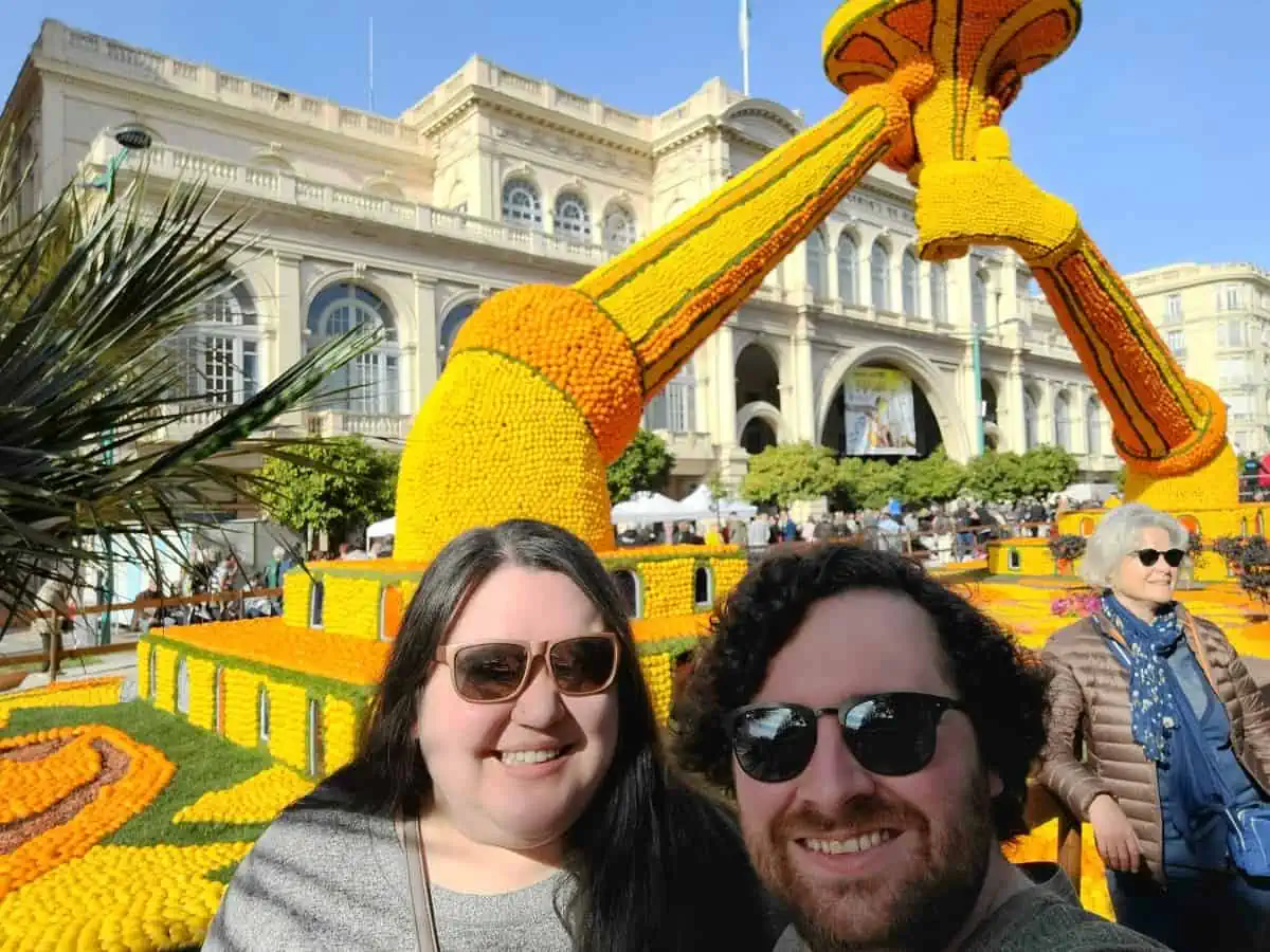 Colin and Riana posing in front of a lemon sculpture of the Olympic torch in Menton, France