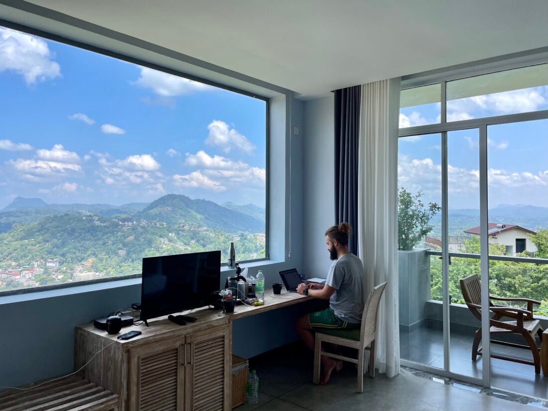 remote worker alex working from digital nomad location with beautiful mountain views and blue skies