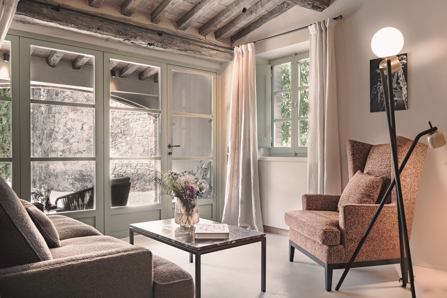 The living room of a garden junior suite at Vocabolo Moscatelli with a large wingback chair and wood beam ceilings