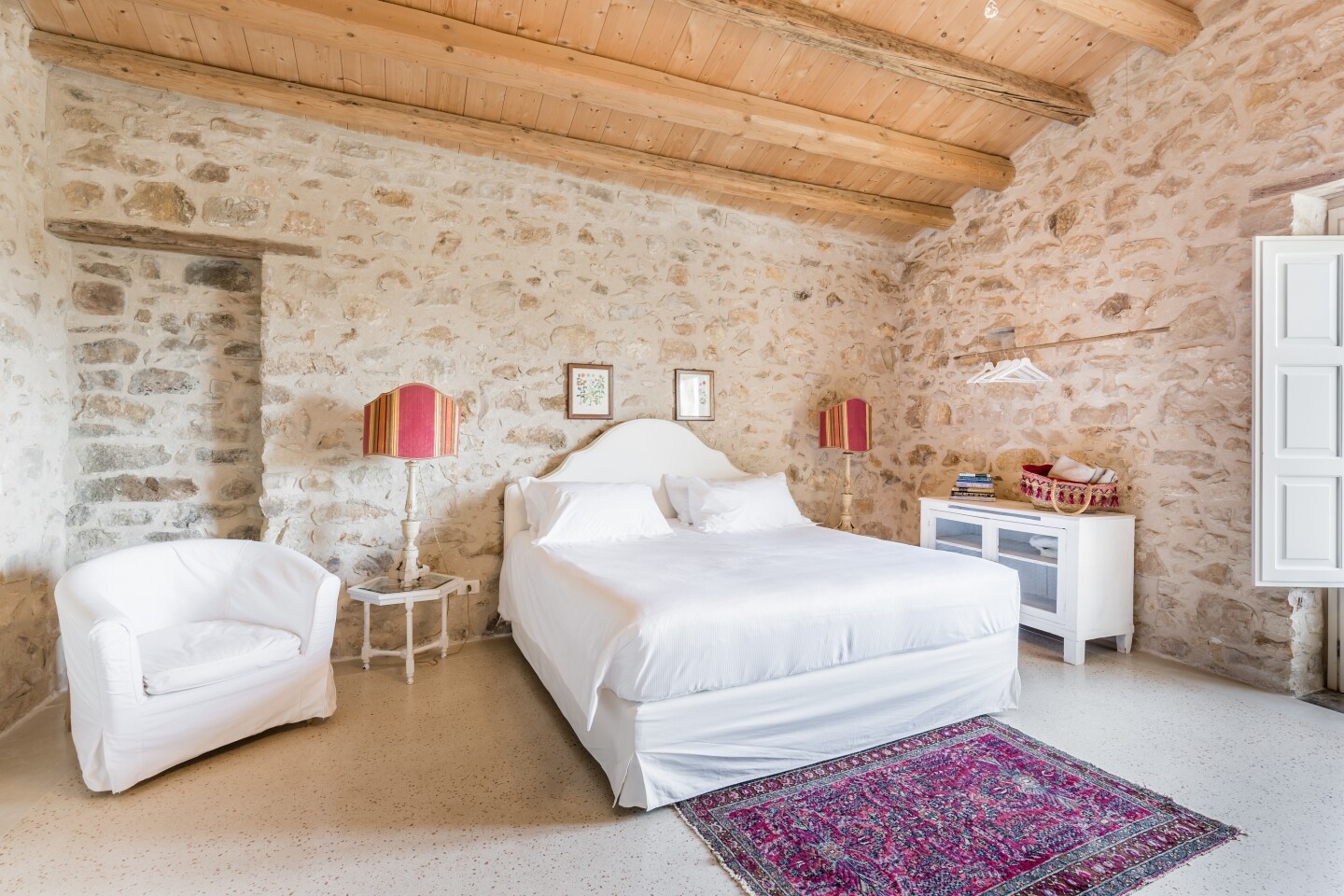 A guest room at Baglio Occhipinti with stone walls and a wood ceiling