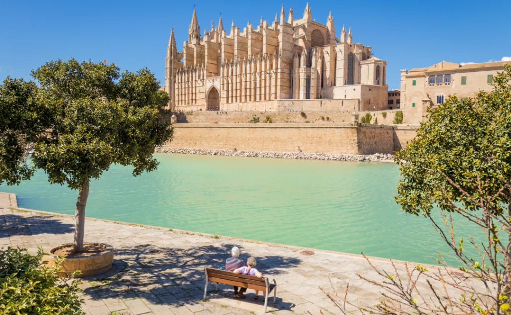 Senior couple having rest at the park near the main cathedral of Palma de Mallorca