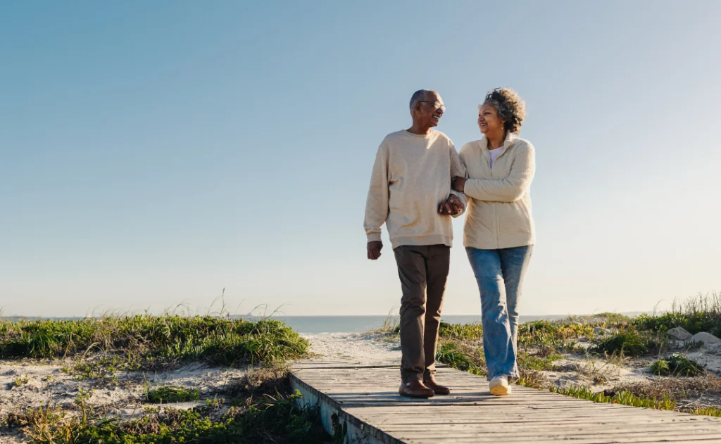 Romantic senior couple walking down a foot bridge at the beach