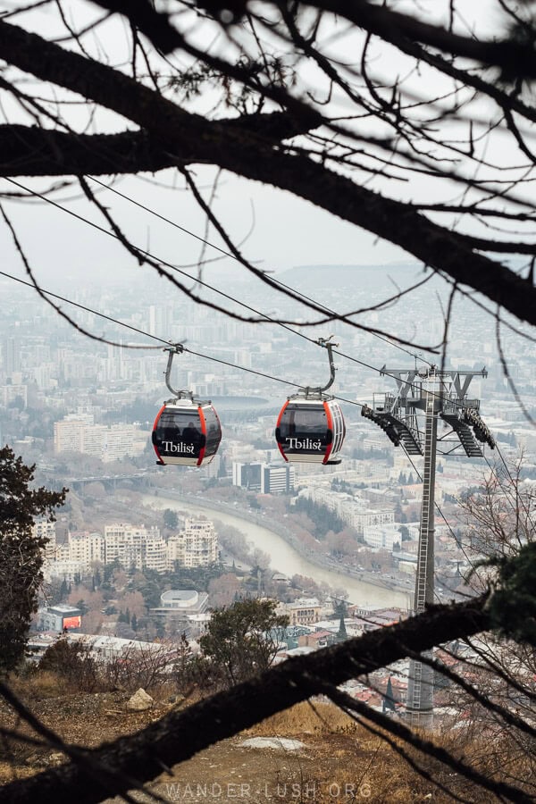 Two Tbilisi cable cars flying over the city and river.