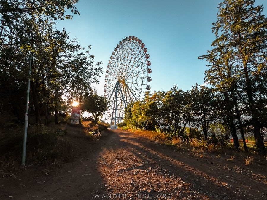 The sun sets behind a Ferris Wheel in Tbilisi's Mtatsminda Park.