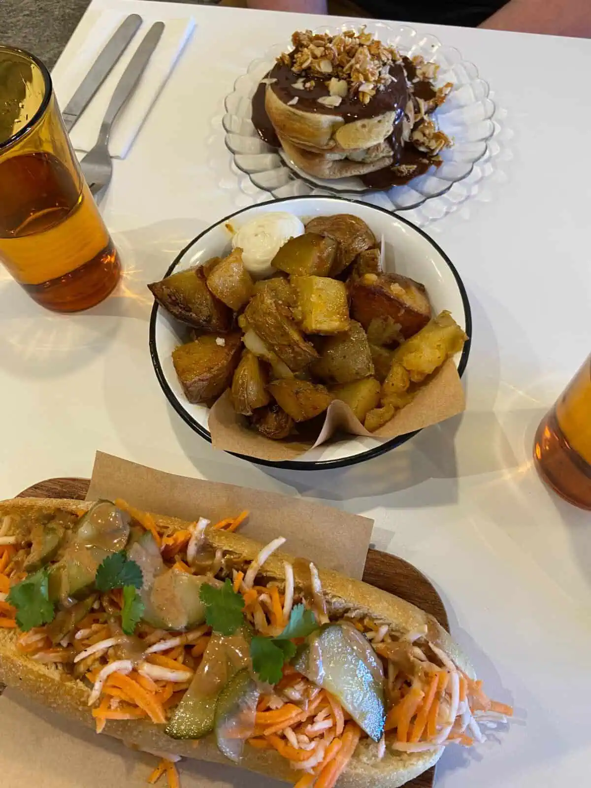 Three dishes enjoyed for brunch in Aix-en-Provence; a banh mi sandwich, a bowl of potatoes, and pancakes covered in chocolate sauce