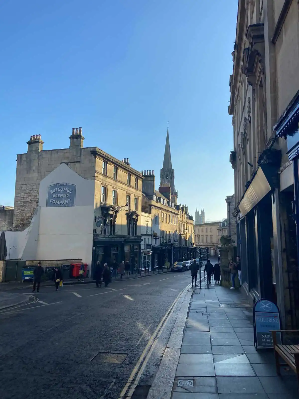 A view down a street in Bath where you can see Georgian buildings and Bath Abbey in the background