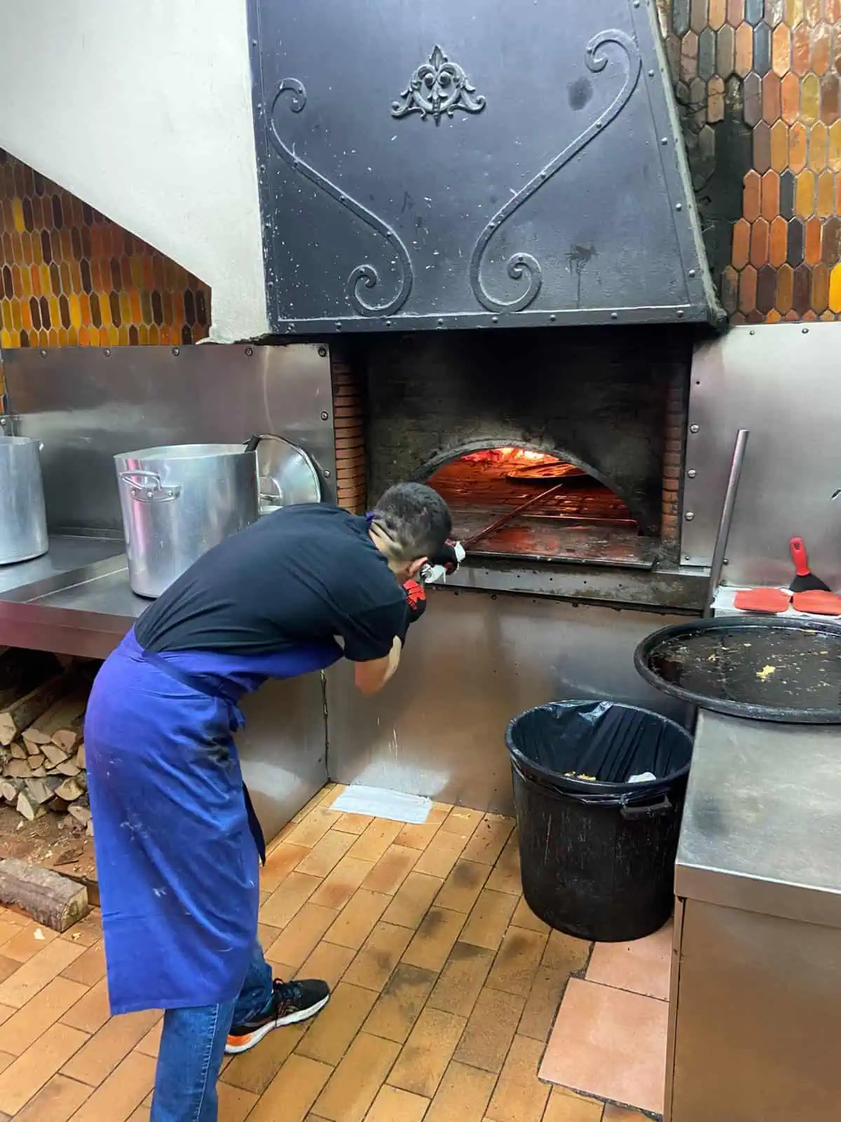 A man leans over an oven where he's cooking socca, a popular Nicoise flatbread