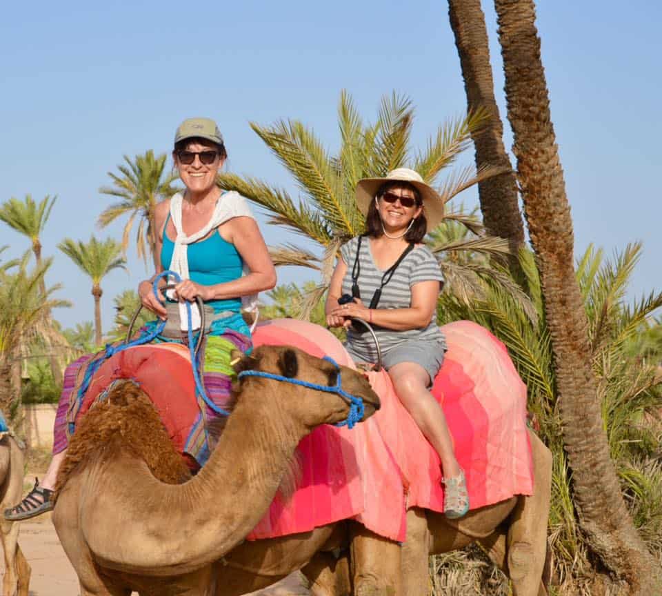 Lyn and Mady riding camels in Marrakesh, Morocco