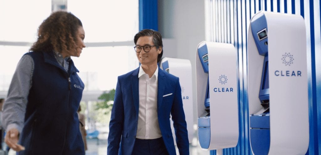 two people standing in front of a row of CLEAR kiosks