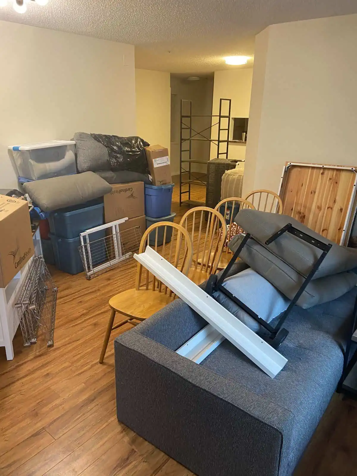 Boxes, bins, chairs, a couch and a shelf in the middle of the living room as we were moving into a new house on moving day