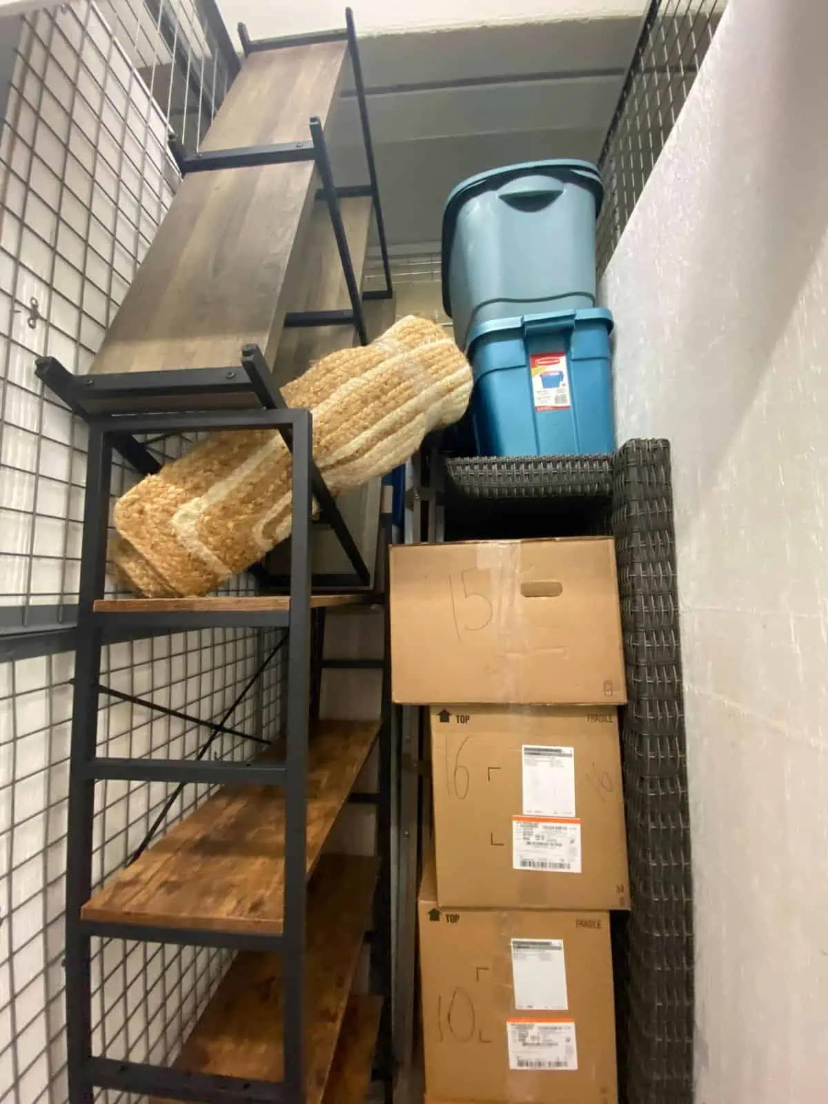 moving boxes, shelves and a desk piled high inside a storage locker