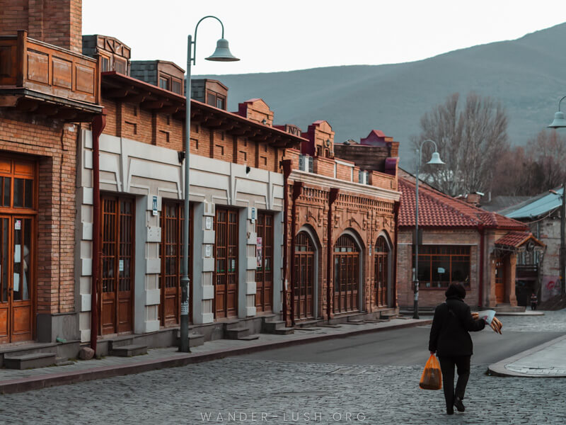 A woman walks down the street holding loaves of bread in Gori, Georgia.