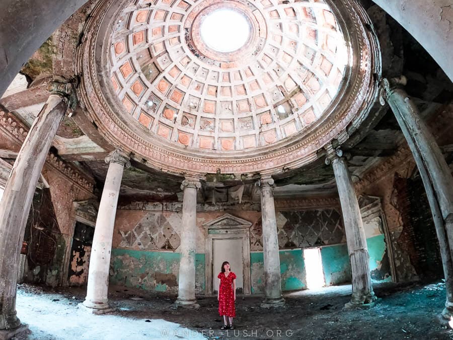 A woman stands beneath the dome of an abandoned sanatorium in Georgia country.