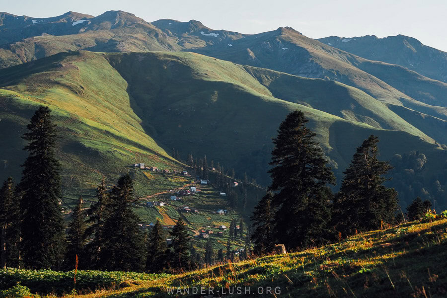 A-frame mountain cottages on a green hillside in Bakhmaro, Georgia.