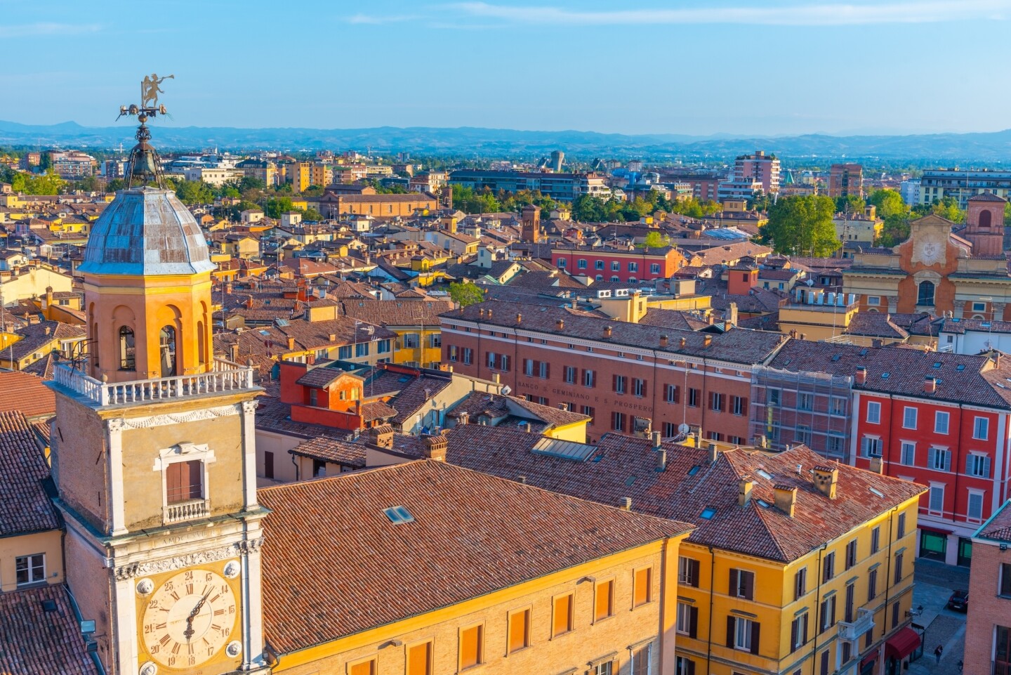 Aerial view of city, with church clock tower (at left) and yellow and red facades of historic buildings